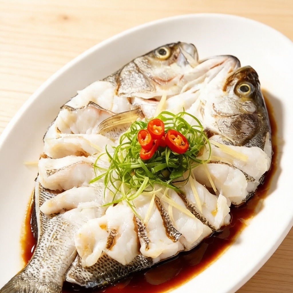 Whole back-scored sea bass on a white plate with spring onion and chilli